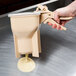 A hand using a Vollrath Batter Boss diffuser to pour batter into a plastic cup.