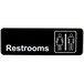 A black Vollrath Traex restroom sign with white text and symbols.