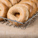 A Clipper Mill chrome wire basket filled with bagels topped with sesame seeds.