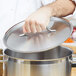 A hand using a Vollrath Optio metal lid to cover a pot.