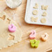 A cookie cutter on a table with cookie dough with different shapes and colors.