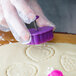A person using an Ateco Valentine's Day plunger cutter to make heart-shaped cookies.