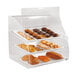 A Vollrath Euro curved front acrylic bakery display case with trays of pastries inside.