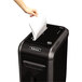 A hand using the Fellowes Powershred 99Ms to shred paper.