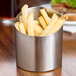 A Tablecraft brushed stainless steel angled cup filled with french fries on a table.