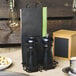 A Clipper Mill black iron Teflon-coated table caddy with salt and pepper shakers on a table with a menu holder.