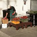 A man in a green apron using a Cambro brown dunnage rack to store tomatoes.