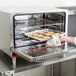 An Avantco electric convection oven rack holding a tray of cookies in an oven.