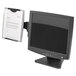 A black computer monitor with a Fellowes black and silver plastic paper holder attached to it.