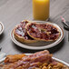 A Tuxton narrow rim brown speckle china plate with bacon, eggs, and toast on a table.