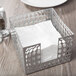 A Clipper Mill gray iron bulge napkin holder with napkins on a table.