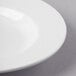 A close-up of a Libbey Basics Orbis bright white porcelain pasta bowl with a curved surface and a thin rim.