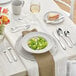 A white table set with silverware including Acopa Monaca stainless steel bouillon spoons.