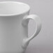 A close-up of a Libbey bright white porcelain tall cup with a handle.