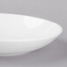 A white Libbey porcelain coupe plate with a rim on a gray surface.