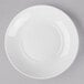 A Libbey Basics bright white porcelain coupe plate with a circular edge on a gray surface.