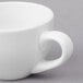 A close-up of a white porcelain espresso cup with a handle.