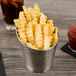 A Tablecraft stainless steel fry cup filled with french fries and a drink.