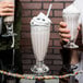 A couple holding Libbey soda glasses filled with milkshakes.