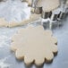 A stainless steel Ateco dahlia flower cookie cutter cutting cookie dough.