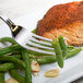 A Bon Chef stainless steel dinner fork on a plate with salmon and green beans.