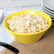 A Tablecraft yellow cast aluminum serving bowl filled with macaroni and cheese.