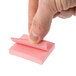 A hand holding a pink Redi-Tag sticky note.