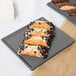 A Tablecraft granite cast aluminum rectangular cooling platter with pastries and a chocolate bar on a table.