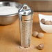 A Fox Run stainless steel fine nutmeg grater on a table with nuts.