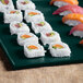 A Tablecraft hunter green and white speckled metal platter with sushi on it.