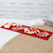 A Tablecraft red cast aluminum rectangular tray with different types of meats on it.