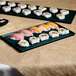 A Tablecraft hunter green and white speckled rectangular metal cooling platter with sushi on a table.
