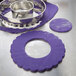 A metal ring cutter with a purple circle-shaped frill on a tray.
