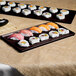 A Tablecraft midnight speckle cast aluminum rectangular cooling platter with sushi on a table.