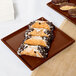 A Tablecraft brown cast aluminum rectangular cooling platter with chocolate covered pastries on a table.