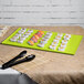 A Tablecraft lime green cast aluminum rectangular cooling platter on a table with sushi and tongs.