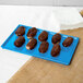 A Tablecraft sky blue cast aluminum rectangular cooling platter holding chocolate covered pastries.