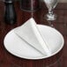 A folded silver linen-like Hoffmaster dinner napkin on a white plate.