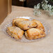 A Fineline clear scalloped plastic catering tray with pastries on a table.