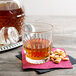 A Libbey Winchester old fashioned glass filled with amber liquid and peanuts on a napkin.