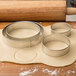 A dough with Wilton metal round cookie cutters on it.