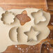 Wilton metal basic shape cookie cutters on cookie dough on a wooden surface.