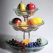 A Clipper Mill stainless steel wire stand with three tiers of fruit on it.