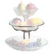 A Clipper Mill stainless steel three tiered fruit stand holding a bowl of fruit.