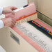 A person opening a file cabinet with a Smead pink file folder.
