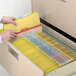 A person opening a file drawer with Smead yellow file folders.