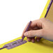 A person's hand holding a yellow Smead SafeSHIELD classification folder with a pen.