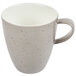 A close-up of a white coffee cup with a speckled design.