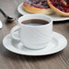 A Schonwald white porcelain saucer with a cup of coffee on it and bread.