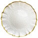 A white glass charger plate with a scalloped rim and gold trim.